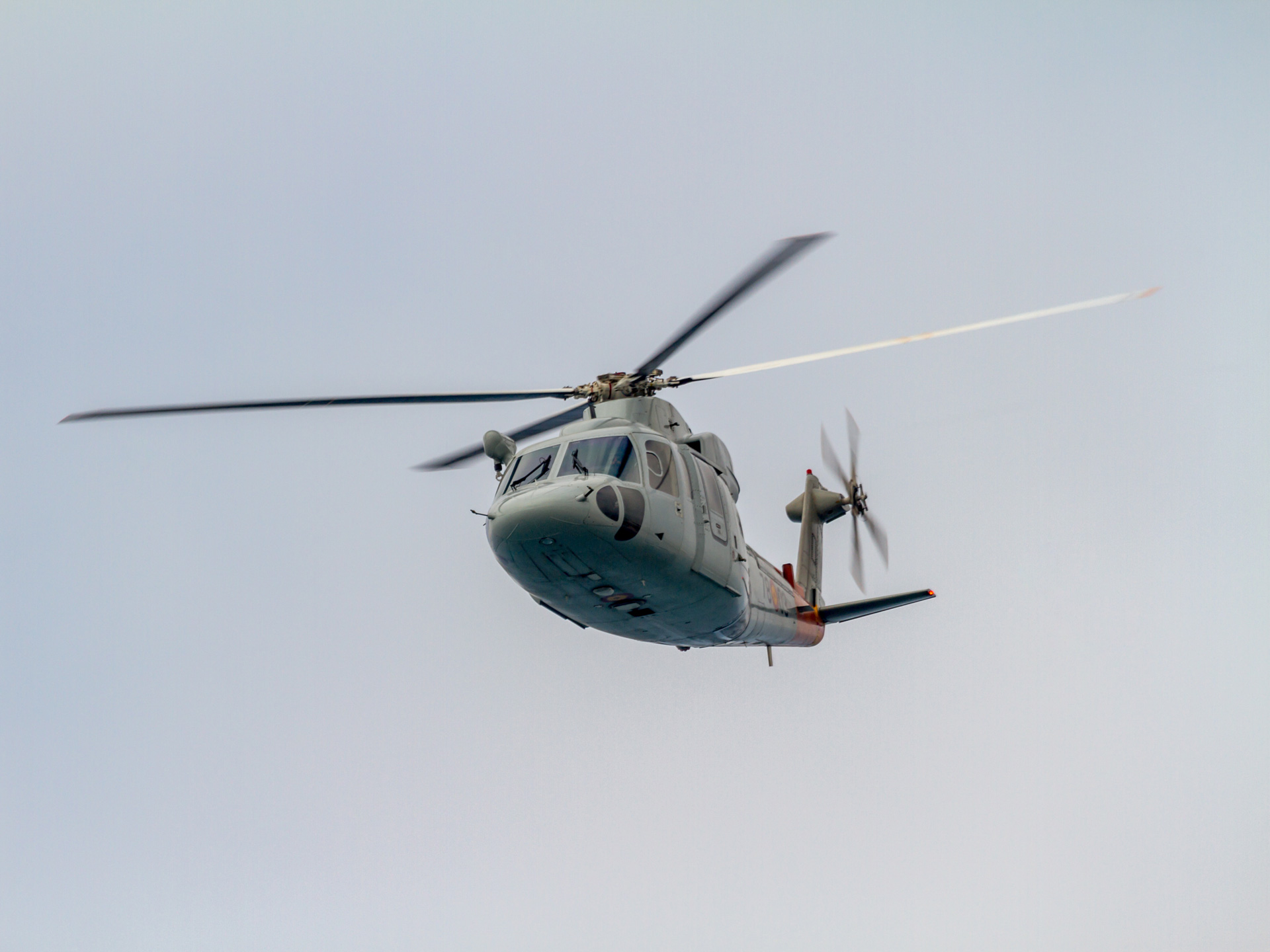 A search and rescue helicopter in flight against an overcast sky
